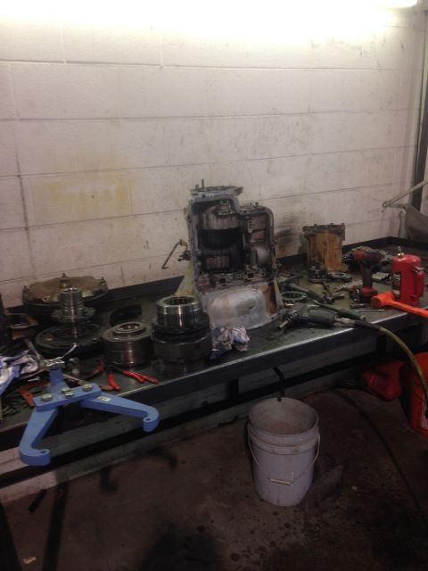1978 Ford Bronco - Various transmission components and tools are spread across a workbench in a workshop setting.