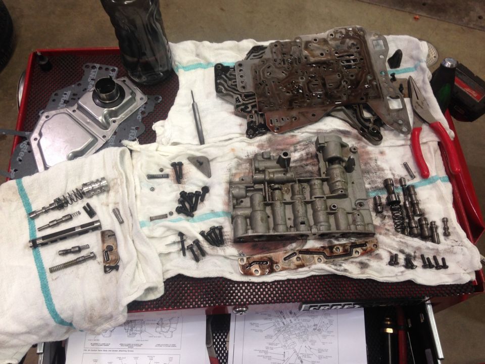 Disassembled automatic transmission valve body and components laid out on towels on a red cart