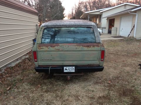 1978 Ford Bronco - This vintage Ford Bronco is parked in a grassy yard next to a building.