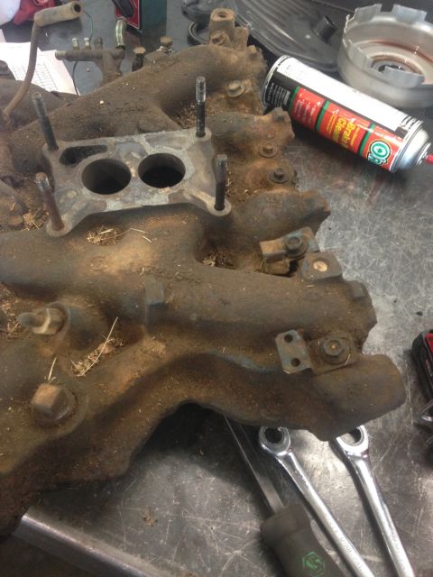 1978 Ford Bronco - Engine intake manifold on a workbench with tools and a can of brake cleaner.