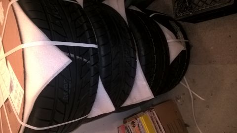 2004 Ford Crown Victoria - Four tires are stacked and secured with straps and protective padding, ready for transport or storage.