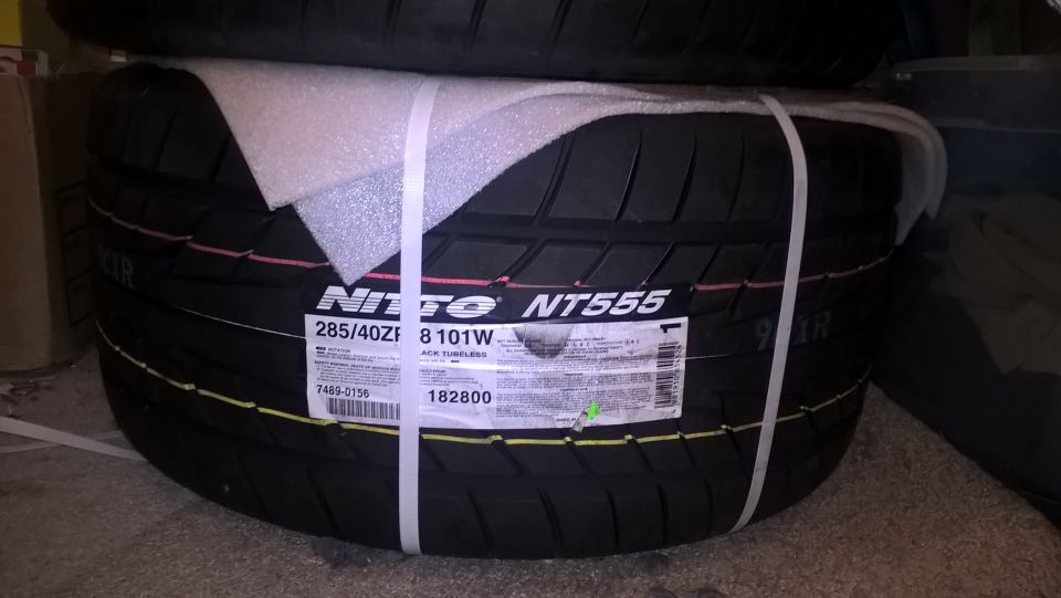 Two stacked Nitto NT555 tires, one with a label showing 285/40ZR 8 101W, secured with white straps