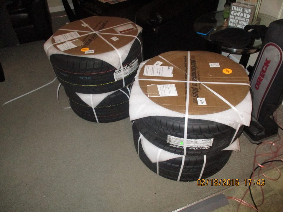 Two stacks of new tires, each wrapped in cardboard and plastic