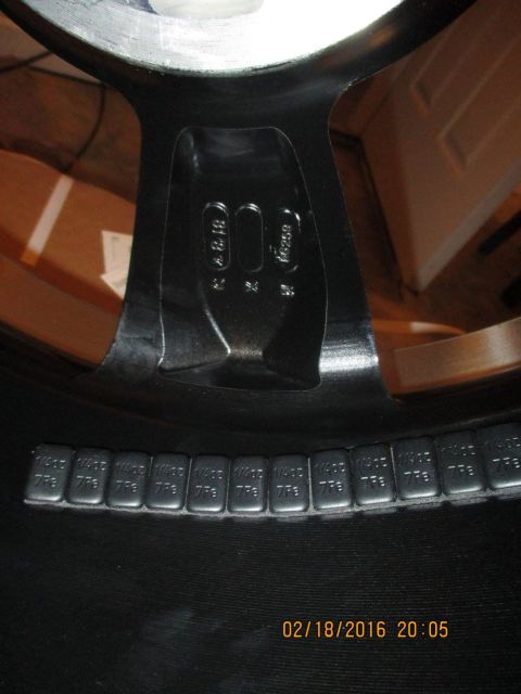 2004 Ford Crown Victoria - A close-up view of a vehicle wheel showing adhesive balance weights and stamped markings on the rim.