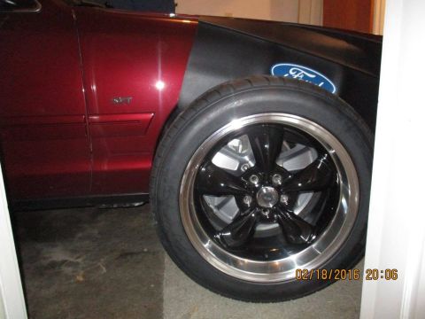 2004 Ford Crown Victoria - A close-up view of a custom black wheel with a polished lip on a red Ford vehicle.