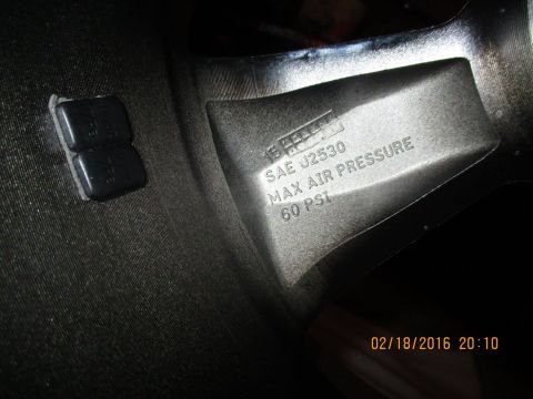 2004 Ford Crown Victoria - Close-up of a wheel rim showing manufacturing markings and valve stem caps.