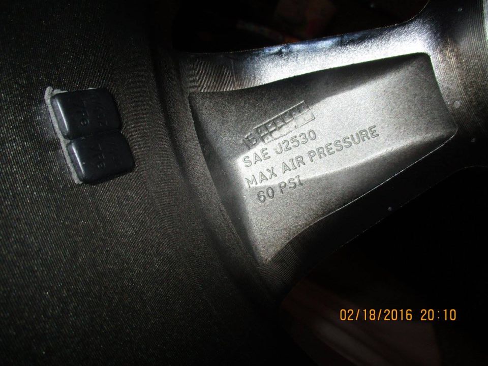 Wheel rim interior showing SAE J2530, MAX AIR PRESSURE 60 PSI markings and two black valve stem caps