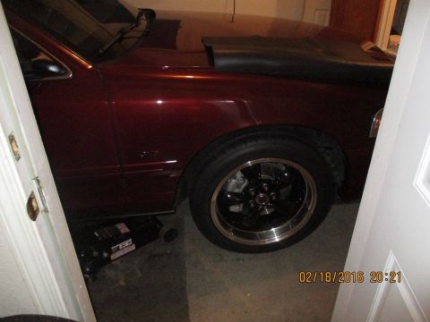 2004 Ford Crown Victoria - A maroon sedan is parked in a garage with a jack supporting the front wheel.