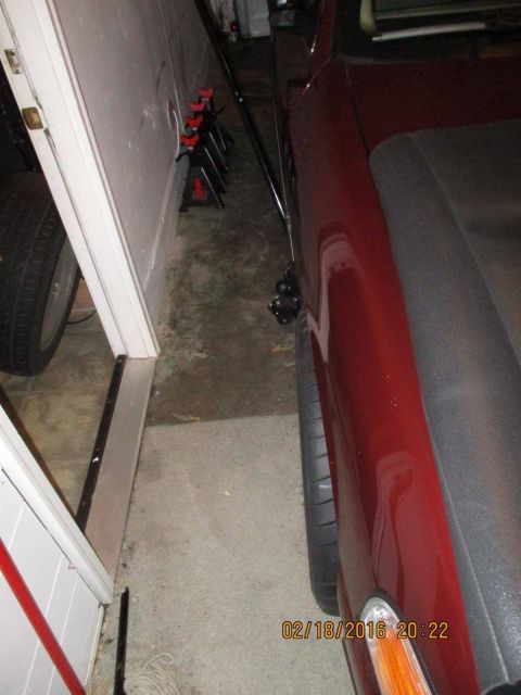 2004 Ford Crown Victoria - A red car is parked very close to a wall in a garage, showing its fender and tire.