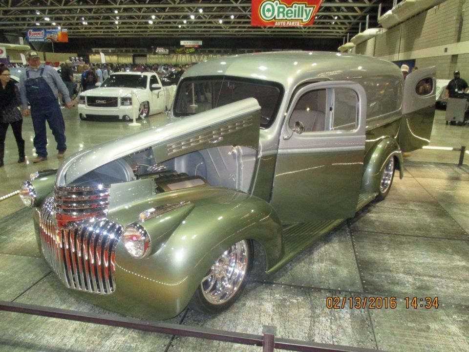 Green custom panel van with hood open, chrome grille, and custom wheels