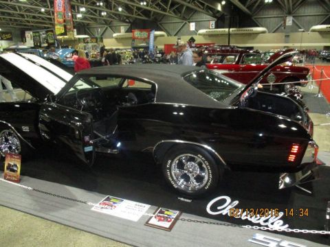 2004 Ford Crown Victoria - Black 1970 Chevrolet Chevelle SS displayed at an indoor car show with other vehicles present.