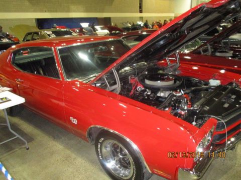 2004 Ford Crown Victoria - Red 1970 Chevrolet Chevelle SS at a car show, engine exposed for viewing.