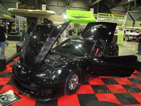 2004 Ford Crown Victoria - A black Chevrolet Corvette is displayed with its hood and doors open, revealing the engine and interior at an indoor event.