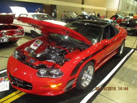 2004 Ford Crown Victoria - Red 1998 Chevrolet Camaro SS with aftermarket turbocharger displayed indoors.