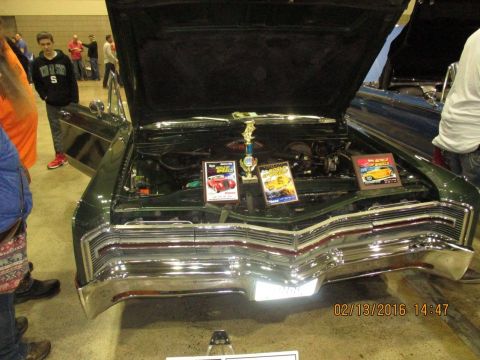 2004 Ford Crown Victoria - A green car is displayed with its hood open, revealing the engine and awards.