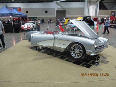 2004 Ford Crown Victoria - Silver 1956 Chevrolet Corvette convertible on display at an indoor event with the hood open.