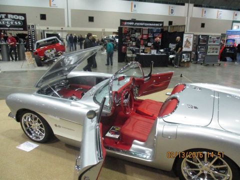 2004 Ford Crown Victoria - A classic silver Chevrolet Corvette is displayed with its doors and hood open at an indoor car show.