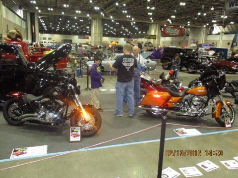 2004 Ford Crown Victoria - Two motorcycles are on display at an indoor event with other vehicles and attendees visible.