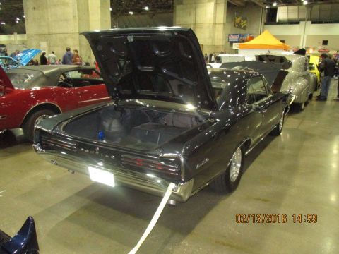 2004 Ford Crown Victoria - A black 1967 Pontiac Grand Prix is displayed with its trunk open, alongside other vehicles.