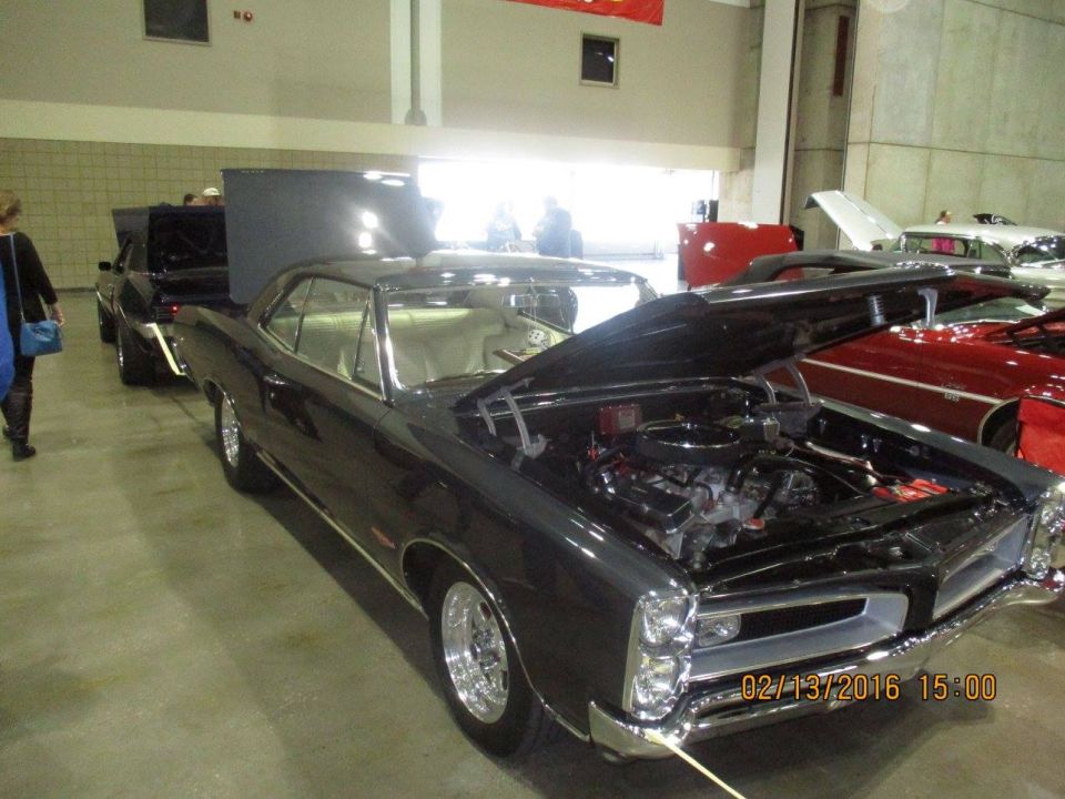 Dark classic car, hood open, showing engine. 1965 model