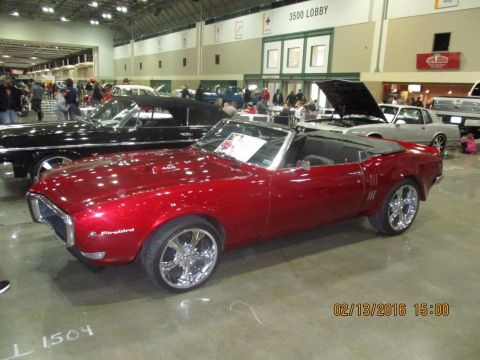 2004 Ford Crown Victoria - Red convertible classic car with chrome wheels at an indoor car show.