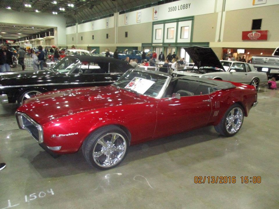 Red convertible classic car with chrome wheels and a black top. "Firebird" script visible on fender