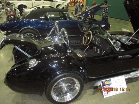 2004 Ford Crown Victoria - A black convertible sports car is displayed alongside other vehicles at an indoor event.