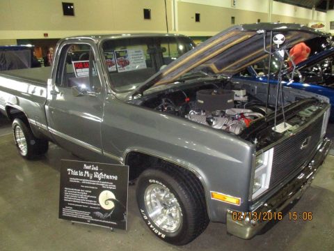 2004 Ford Crown Victoria - A custom gray pickup truck is displayed with its hood open, revealing the engine and a sign referencing 'The Nightmare Before Christmas'.