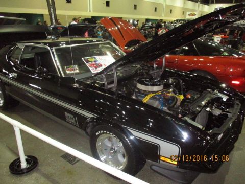 2004 Ford Crown Victoria - Black 1971 Ford Mustang Mach 1 displayed with its hood open at an indoor car show.