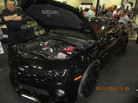 2004 Ford Crown Victoria - A black Chevrolet Camaro SS is displayed with its hood open, revealing the engine and an "SS" emblem.
