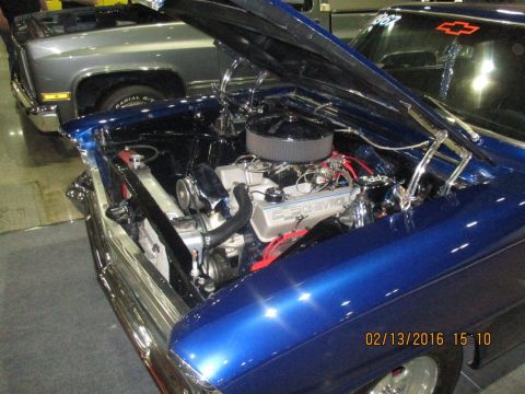 2004 Ford Crown Victoria - A blue classic car's engine bay is open, revealing its V8 engine and chrome details, with another vehicle in the background.
