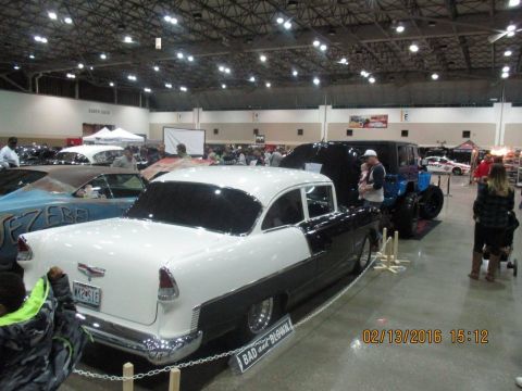 2004 Ford Crown Victoria - A classic two-tone car is displayed indoors at an event, with other vehicles and people visible in the background.