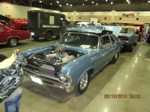 2004 Ford Crown Victoria - A blue classic car with its hood open is displayed indoors, alongside other vehicles.
