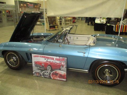 2004 Ford Crown Victoria - A light blue 1961 Chevrolet Corvette convertible is displayed with its hood open.