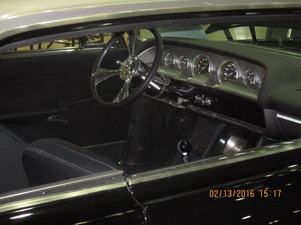 Interior view of a classic car with a custom steering wheel and dashboard gauges