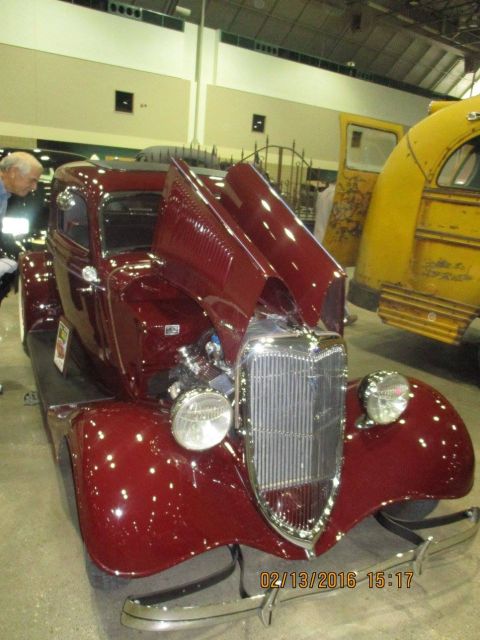 2004 Ford Crown Victoria - A maroon vintage car is displayed with its hood open, revealing the engine, next to a yellow bus.