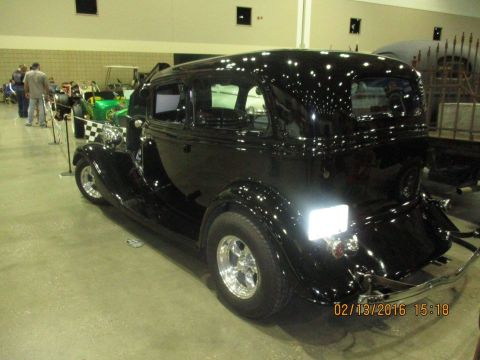 2004 Ford Crown Victoria - A black hot rod sedan is displayed indoors, with other vehicles in the background.