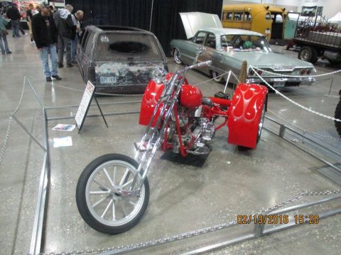 2004 Ford Crown Victoria - A custom red trike with flame decals is displayed at an indoor event.