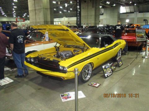 2004 Ford Crown Victoria - Yellow 1970 Dodge Challenger on display with hood open, other vehicles visible in background.