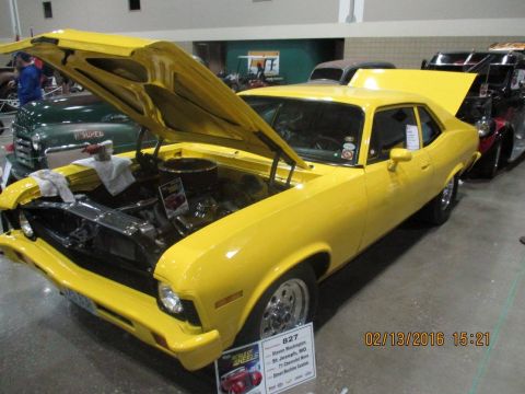 2004 Ford Crown Victoria - A bright yellow 1971 Chevrolet Nova is displayed with its hood open, alongside other vehicles at a show.