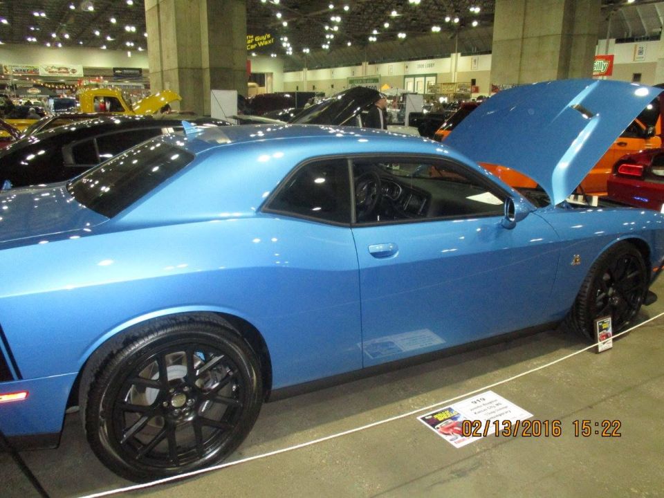 blue Dodge Challenger with hood open, parked indoors at a car show