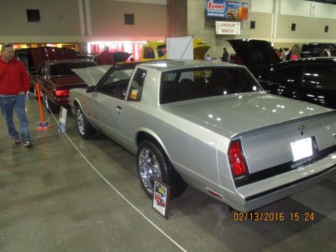 2004 Ford Crown Victoria - A silver Chevrolet Monte Carlo is displayed at an indoor event with other vehicles present.