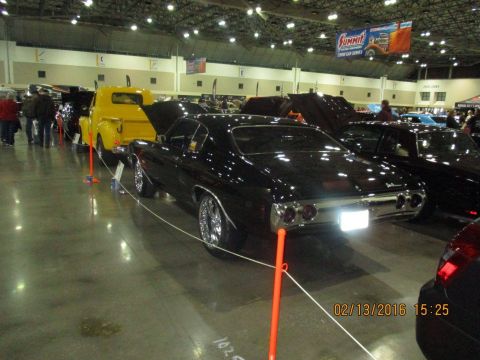 2004 Ford Crown Victoria - A black classic car is displayed at an indoor event, with a yellow truck visible in the background.