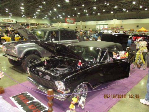2004 Ford Crown Victoria - Two vehicles, a black convertible and a silver SUV, are displayed indoors with their hoods open.