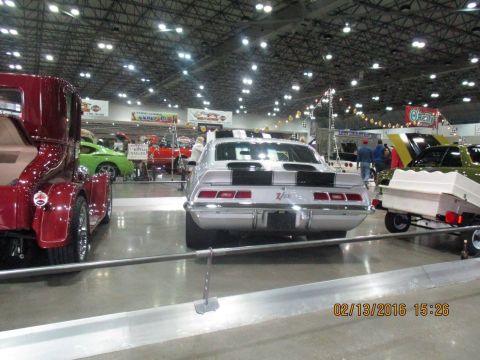 2004 Ford Crown Victoria - A silver 1969 Chevrolet Camaro Z/28 is displayed indoors with other vehicles, including a red truck and a green car.