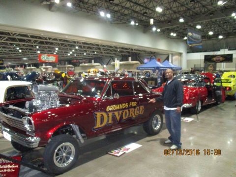 2004 Ford Crown Victoria - A man stands next to a customized maroon hot rod at a car show.