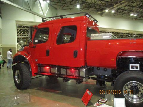 2004 Ford Crown Victoria - A bright red crew cab truck with a chrome toolbox and roof rack is on display indoors.