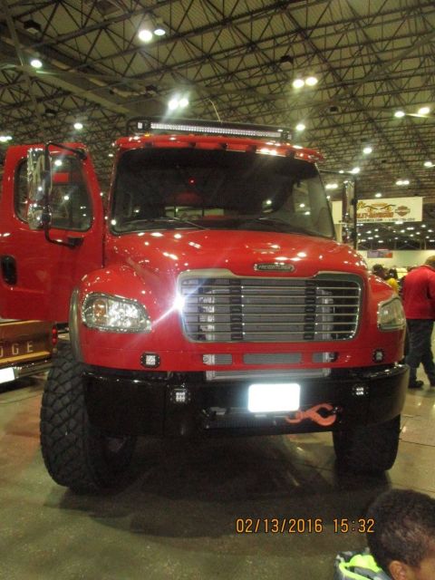 2004 Ford Crown Victoria - A red Freightliner truck is displayed indoors with its driver's side door open and a prominent light bar above the windshield.