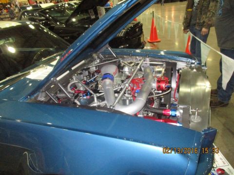 2004 Ford Crown Victoria - Modified engine bay of a blue car at an indoor event, with other vehicles in the background.