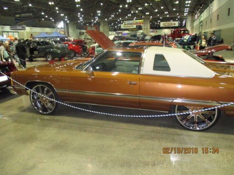 2004 Ford Crown Victoria - This customized coupe with a white vinyl top and large chrome wheels was displayed at an indoor event.